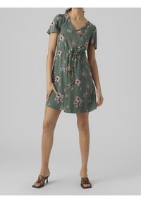 Robe florale verte à manches courtes, décolleté en V, taille cintrée et jupe évasée. Avec des motifs floraux roses et bleus.