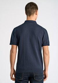 Granatowa dzianinowa koszulka polo z krótkimi rękawami, płaskim kołnierzykiem i prążkowanym dołem. Minimalistyczny design bez wzorów i zdobień.