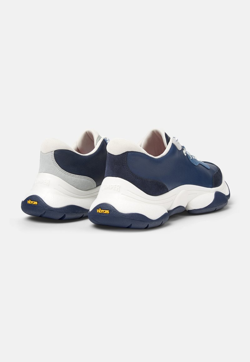Sneaker blu e grigie realizzate in pelle e camoscio. Presentano una suola intermedia bianca e una suola Vibram, accentuate da lacci azzurri.