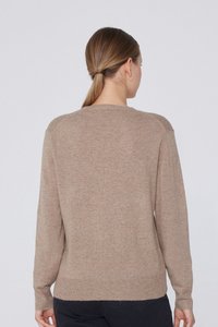Sweter dziergany w miękkim odcieniu beżu, z okrągłym dekoltem, długimi rękawami i prążkowanym wykończeniem. Gładka faktura z minimalną ilością szwów i czystymi liniami.