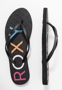 Svarte flip-flops med strukturert såle som har flerfargede bokstaver: rosa "R," oransje "X," lys blå "Y," og hvit "O." Svarte stropper.