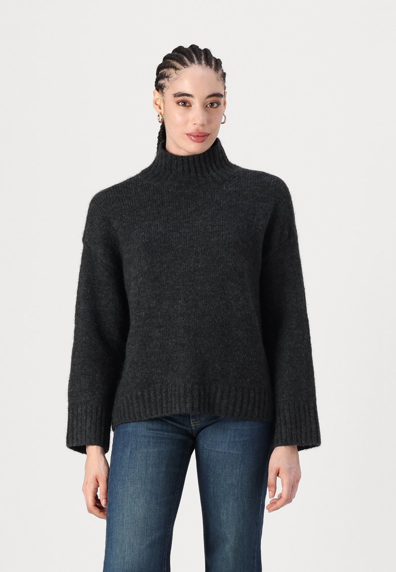 Pulover supradimensionat, de culoare gri închis, cu guler înalt, realizat dintr-un tricot moale și texturat. Are mâneci largi și un tiv cusut în relief pentru un detaliu suplimentar.