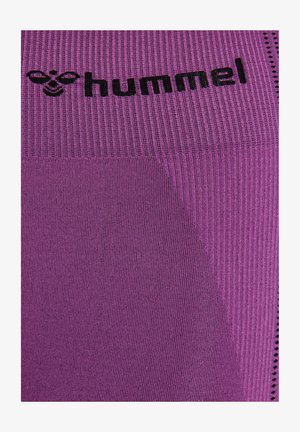 Close-up van paars gestructureerde stof met zwart "hummel" logo en bijenembleem gebreid vlakbij de bovenkant.