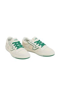 Vita sneakers med gröna accenter och snören, med en texturerad design och en framträdande Vans-logga på plösen och sidan.