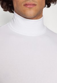 Weißes Rollkragenhemd aus glattem, elastischem Stoff, mit eng anliegendem Kragen und minimalistischem Design ohne sichtbare Muster.