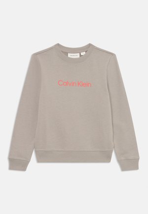 Grå sweatshirt med rund hals, ribbestrikkede mansjetter og nederkant; har et fremtredende rosa "Calvin Klein"-logo på forsiden. Myk stoffkvalitet.
