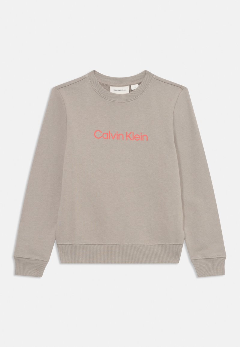 Felpa grigia con collo tondo, polsini e orlo a costine; presenta un logo "Calvin Klein" rosa ben visibile sul davanti. Tessuto morbido.