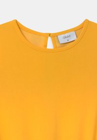 Vestido amarelo com decote redondo e abertura em formato de olho de fechadura nas costas. Feito de um tecido suave, com uma cor sólida e sem padrões visíveis.