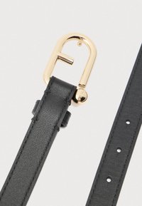 Melnas ādas josta ar zelta D veida sprādzi. Raksturīgas iezīmes: gluda tekstūra, vairāki caurumi regulēšanai un zīmola uzraksts uz sprādzes.