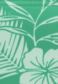 Tessuto verde con una trama a coste che presenta un motivo di foglie tropicali e fiori in verde chiaro, con cuciture a contrasto lungo i bordi.