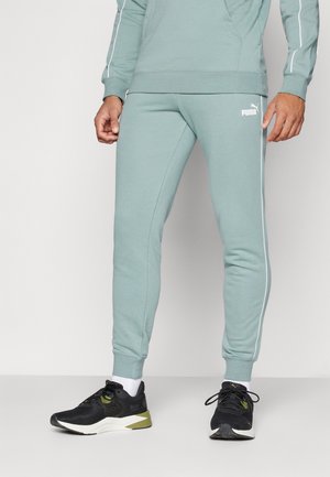 Light green joggers with white side stripes and a PUMA logo, made of soft fabric. Paired with black athletic shoes and white socks.