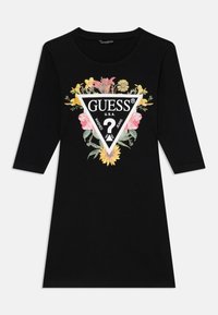 Rochie neagră din bumbac cu mâneci trei sferturi; include un grafic floral care înconjoară un triunghi alb cu logo-ul și textul "GUESS".