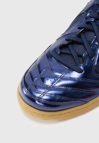 Γυαλιστερό ναυτικό μπλε πάνινο παπούτσι με υφή στην επάνω επιφάνεια, ραφές κ�αι στρογγυλή μύτη. Διαθέτει σόλα από καουτσούκ σε γκρι απόχρωση και σκούρα κορδόνια.