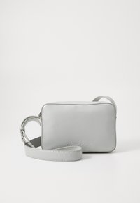 Borsa a tracolla in pelle grigia di forma rettangolare, con chiusura a zip e tracolla regolabile. Logo "Calvin Klein" impresso sulla parte anteriore.