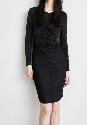 Schwarzes langärmeliges Kleid mit gerafftem Design und schimmernder Textur. Figurschnitt und geraffte Details entlang der Vorderseite.