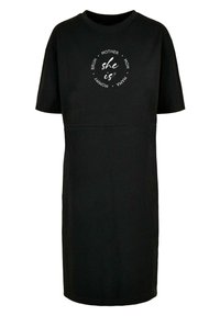 Svart bomull t-shirt klänning med korta ärmar, rund halsringning och en grafisk cirkeldesign med texten "hon är" och relaterade ord.