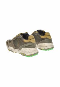 Sneaker verde scuro e beige con una tomaia strutturata, suola bianca maculata e dettagli in gomma verde sulla suola esterna.