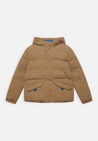 Hnědá péřová bunda s kapucí, s předním zipem, dvěma šikmými kapsami a modrými akcenty. Logo Lacoste je vyšité na prsou.
