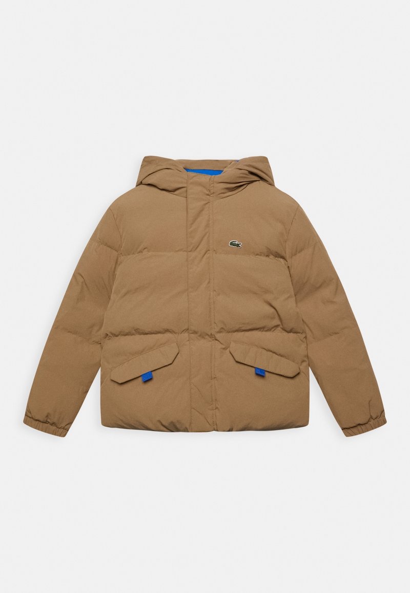 Hnědá péřová bunda s kapucí, s předním zipem, dvěma šikmými kapsami a modrými akcenty. Logo Lacoste je vyšité na prsou.