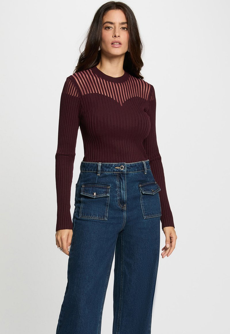 Haut à manches longues côtelé bordeaux avec des accents rayés transparents sur les épaules, associé à un jean large taille haute bleu foncé avec poches.