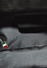 Zilveren bedel met een golvend ontwerp van de Italiaanse vlag in groen, wit en rood, gelegen in een tekstuur van zwart stof.
