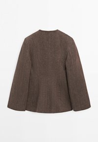 Bruine blazer met lange mouwen van een gestructureerde stof, met gevormde naden en een ontwerp zonder kraag, gezien van achteren tegen een witte achtergrond.