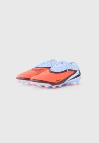 Par noge narančastih i svijetloplavih Nike nogometnih kopački s vezicama i kopačima, postavljenih jedna pored druge na bijeloj pozadini.