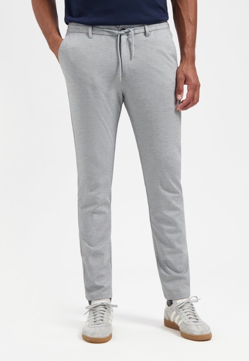 Grijze, aansluitende joggingbroek van zachte stof, met een elastische tailleband met trekkoord, zijzakken en taps toelopende pijpen.