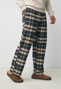 Beige och marinblå rutiga loungebyxor med en lös passform, elastisk midja och sidofickor. Mjuk tyg med rutig mönsterdetaljer.