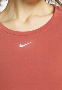 Camiseta de algodón roja con diseño de cuello redondo. Presenta un pequeño logo blanco de Nike en el pecho. Textura suave, corte casual.