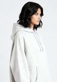 Grijze hoodie van zachte stof, voorzien van een kangoeroezak en capuchon met trekkoord. Losse pasvorm met verlaagde schouders voor comfort.