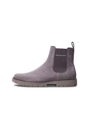 Bottine Chelsea en daim gris avec panneau latéral en élasthanne côtelé, marque "Calvin Klein Jeans", et semelle épaisse à crampons.