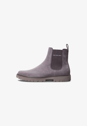 Bottine Chelsea en daim gris avec panneau latéral en élasthanne côtelé, marque "Calvin Klein Jeans", et semelle épaisse à crampons.