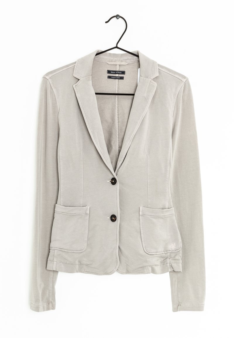 Blazer casual gris clair avec deux boutons, deux poches avant, manches longues et col à revers cranté, accroché à un cintre noir.