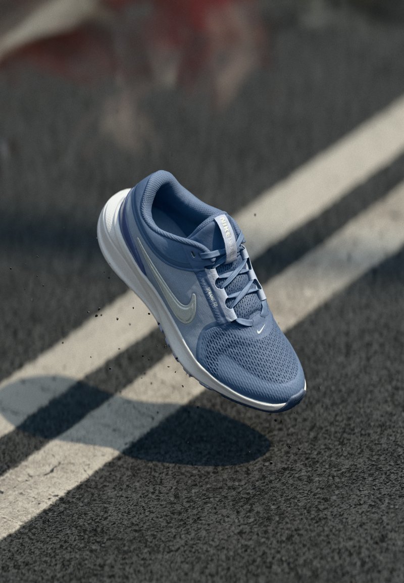 Svijetloplavi atletski tenisice s mrežastim gornjim dijelom, bijelim potplatom i reflektirajućim detaljima, s dizajnom na vezanje i istaknutim swoosh logotipom.