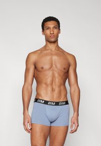 Helleblaue Boxershorts mit schwarzem Bund, der mit dem "DIM"-Logo versehen ist. Glattes, weiches Material; enganliegendes Design, das die Körperform betont.