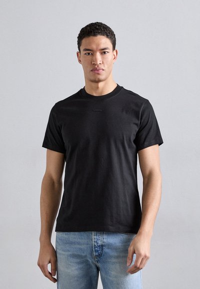T-shirt en coton noir avec un col rond et des manches courtes. Présente une marque minimale sur la poitrine et une coupe décontractée.