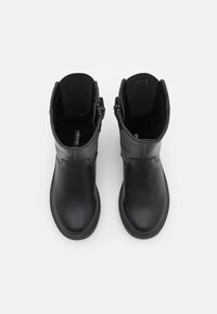 Bottines en cuir noir avec une texture lisse, bout rond et détail de fermeture éclair sur le côté. L'intérieur est doublé pour plus de chaleur et de confort.