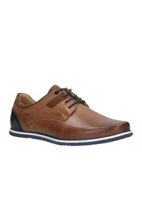 Scarpa in pelle marrone con una finitura liscia, tacco blu navy a contrasto e suola striata bianco-blu; presenta un design con lacci e cuciture decorative.