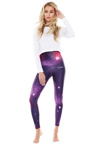 Hochtaillierte Leggings in einem lila Galaxie-Druck mit Sternmustern, aus dehnbarem Stoff. Das Oberteil ist ein weißes langärmliges Croptop.