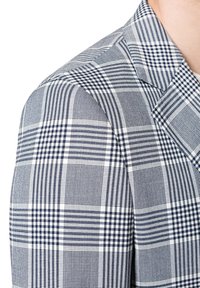 Marynarka w kratę w niebiesko-białym wzorze, z wyraźnymi ramionami, ostrymi klapami oraz teksturowanym wykończeniem.