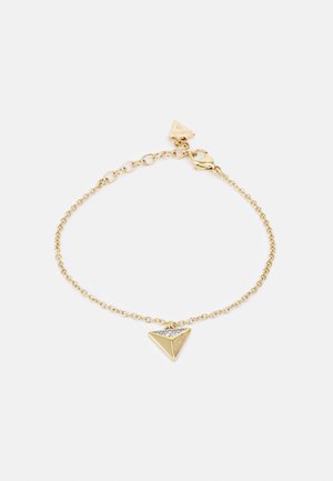 Gold chain bracelet with adjustable links and triangular charm featuring small crystals and engraved brand name "Guess".