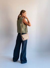 Olivovo zelený cropped top, široké tmavé denimové nohavice a béžová crossbody taška. Hladké textúry a minimalistický dizajn.