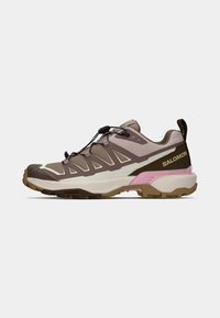 Salomon trail sko i brun, tan og pink. Har en struktureret overdel, snøresystem og robust sål for godt greb.