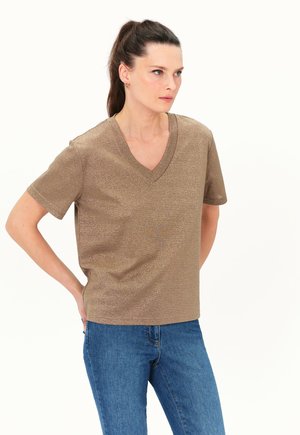 Bronzefarbenes V-Ausschnitt-T-Shirt mit kurzen Ärmeln aus schimmerndem Material. Kombiniert mit blauen Jeans. Schlichtes, lässiges Design.