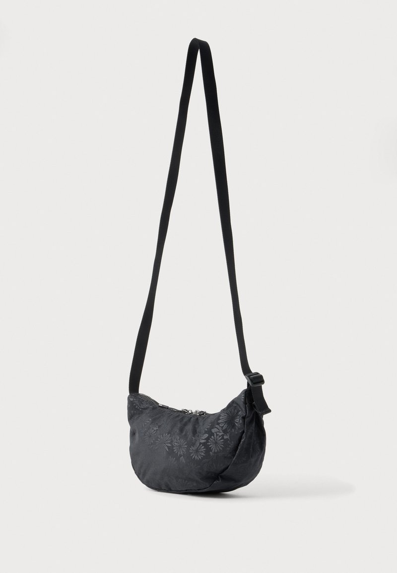 Schwarze Umhängetasche mit langem verstellbarem Riemen und dezentem Blumenmuster, vor einem schlichten hellen Hintergrund hängend dargestellt.