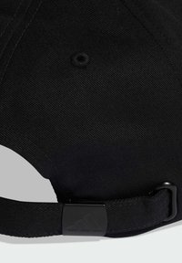 Black cap made of textured fabric. Features a curved brim, adjustable strap with black hardware, and a top button. Simple design.