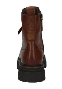 Braunes Lederanhkleboot mit dicker schwarzer Sohle, sichtbaren Nähten, seitlichem Reißverschluss und geprägtem Logo auf dem hinteren Element.