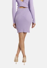 Lila geripptes Kleid mit langen Ärmeln und taillierter Silhouette, mit offenem Rücken und knielangem Saum, kombiniert mit beigen Stiletto-Heels.