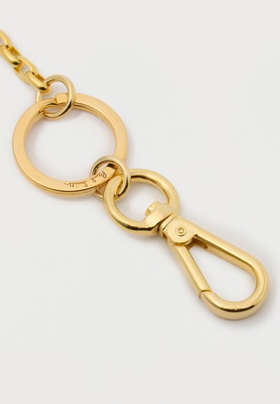 Portachiavi in metallo dorato con anello circolare e clip a graffio, superficie liscia, finitura lucida, con un piccolo dettaglio inciso sull'anello.